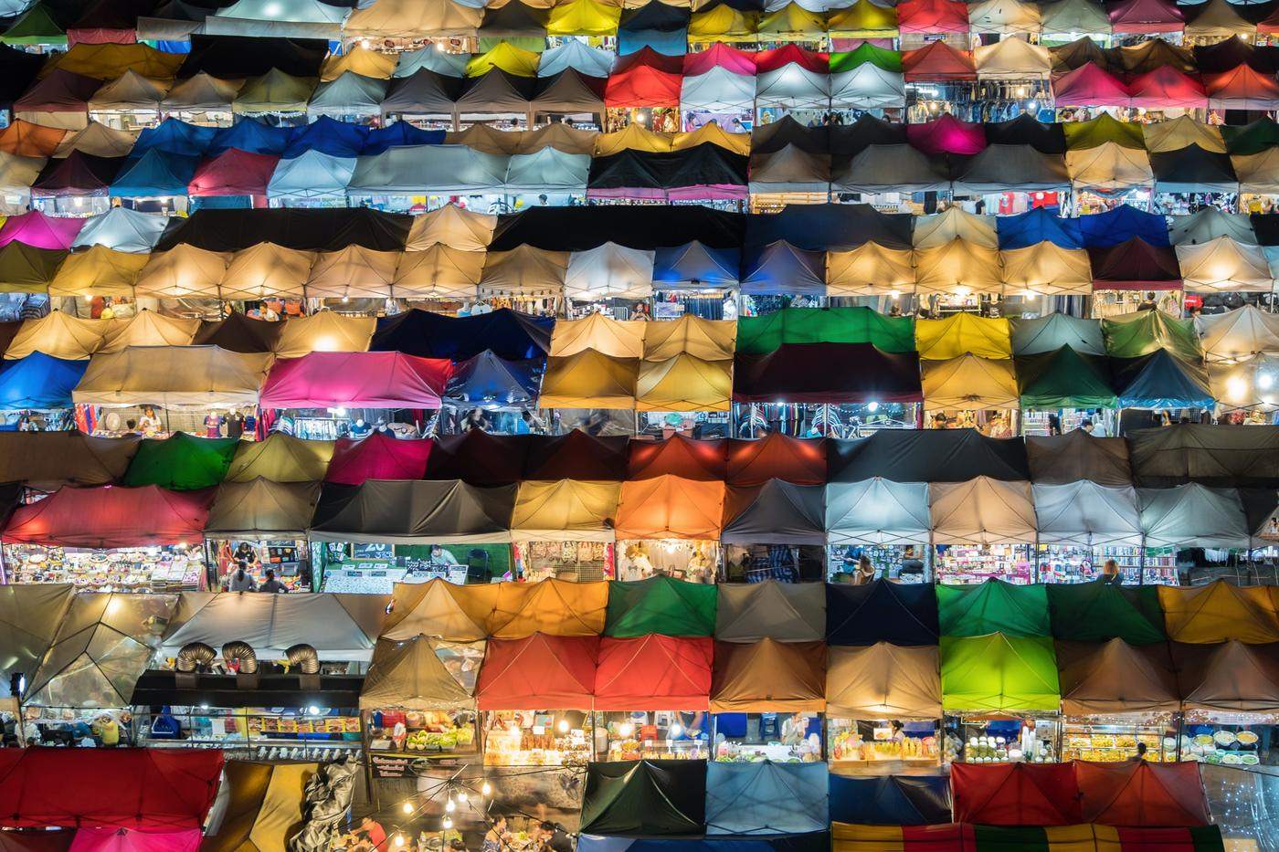 Rows of colorful lit tents at a night market seen from above