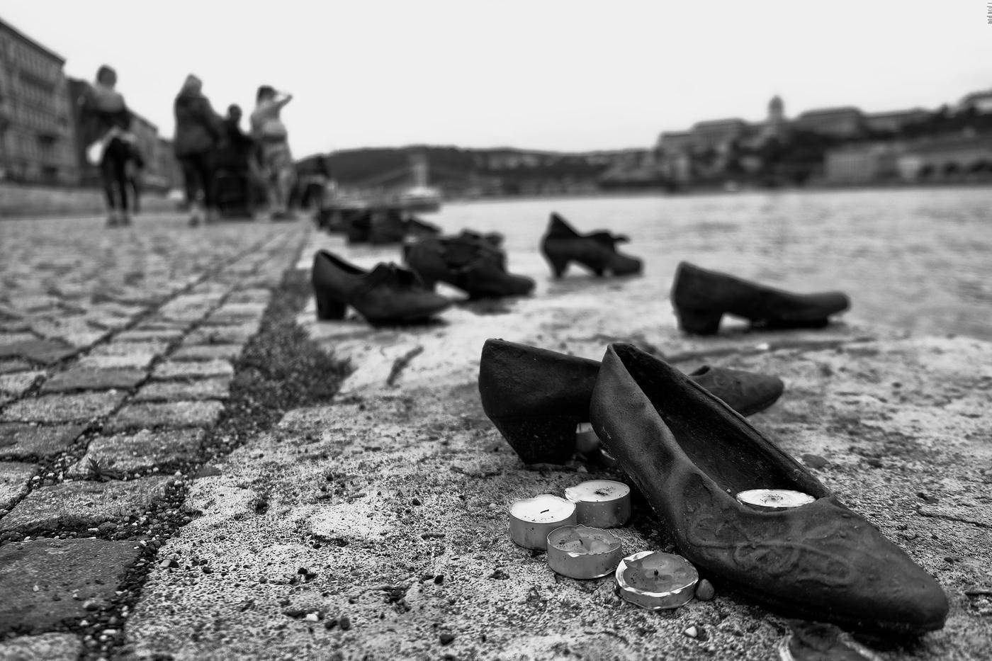 Iron shoes and tea lights on a riverbank memorial