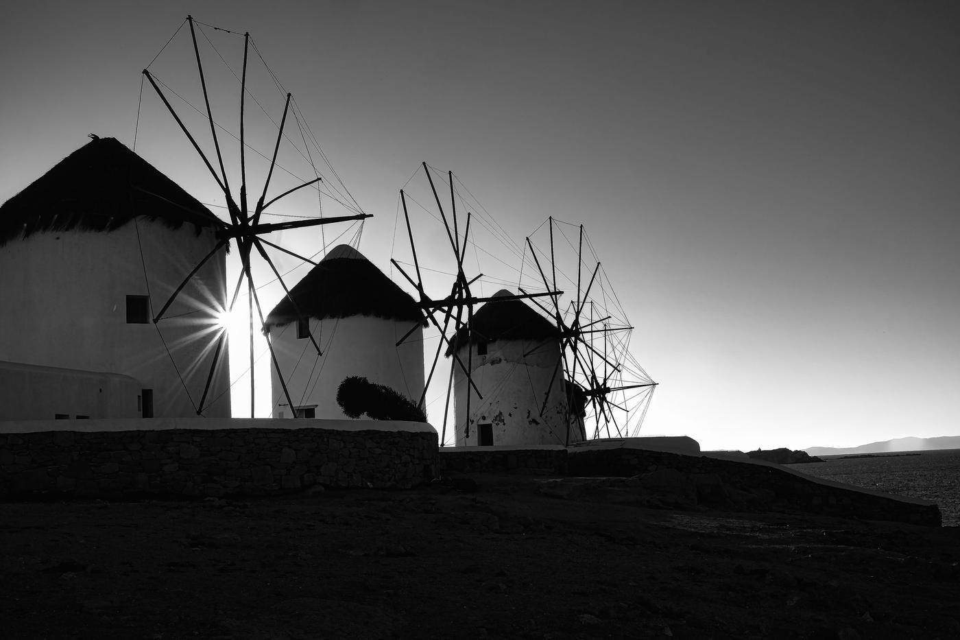 Windmills silhouetted with a sunburst between them
